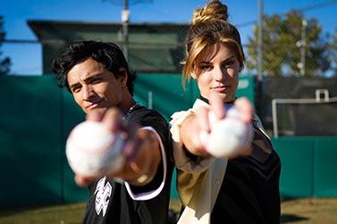 A man and a woman both holding Baseballs out to the camera